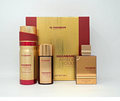 Al Haramain Amber Oud perfume gift set featuring a large gold and red box, a tall cylindrical bottle with a red cap, a smaller dark bottle with a gold cap, and a rectangular perfume bottle with a gold cap, all on a white background.