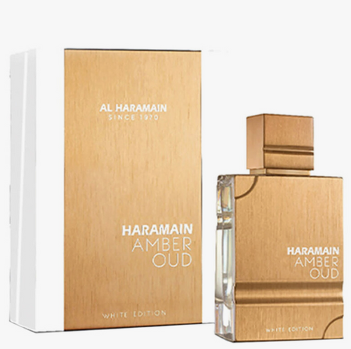 Al Haramain Amber Oud White Edition perfume bottle and its matching outer packaging box, both featuring a brushed gold finish with white lettering, set against a plain white background.Al Haramain Amber Oud White Edition Unisex Eau de Parfum 60ml gold brushed metal bottle with matching white and gold gift box - Authentic Perfume Store UPC 6291100131617