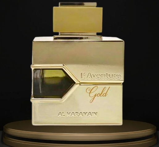 Al Haramain L'Aventure Gold perfume bottle in a metallic gold finish, displayed on a matching gold circular pedestal against a black background.
