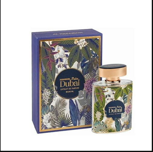 A bottle of Al Haramain palm Dubai Extrait de Parfum next to its blue packaging box, both decorated with a tropical floral and leaf pattern and featuring a gold-toned cap.