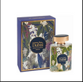 A bottle of Al Haramain palm Dubai Extrait de Parfum next to its blue packaging box, both decorated with a tropical floral and leaf pattern and featuring a gold-toned cap.