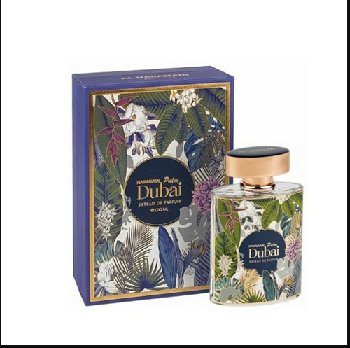 A bottle of Al Haramain palm Dubai Extrait de Parfum next to its blue packaging box, both decorated with a tropical floral and leaf pattern and featuring a gold-toned cap.