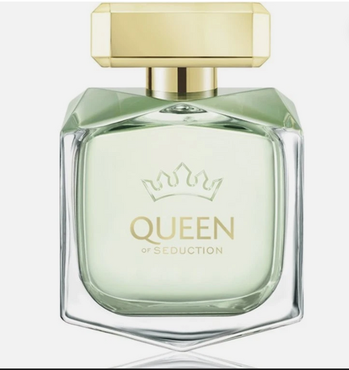 Queen of Seduction perfume bottle with a faceted clear glass body, pale mint green liquid, and a gold cap, shown on a light gray background.
