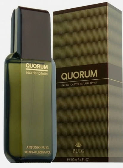 Aqua Quorum Eau de Toilette spray box in dark blue with gold diagonal lines, a red label with gold lettering, and a yellow top and bottom trim. A blue spray bottle is partially visible on the right side.