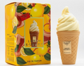 A perfume bottle shaped like a soft-serve ice cream cone stands next to its illustrated box. The packaging is bright yellow with lemon and orange graphics, and the bottle itself is tan with a pale yellow ice cream swirl on top.