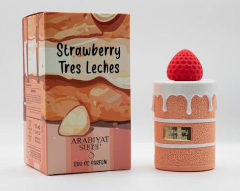 A perfume bottle shaped like a strawberry-topped pastry next to its illustrated retail box. The packaging reads 'Strawberry Tres Leches' and 'ARABIYAT SUCRE', with peach, cream, and red-orange artwork.