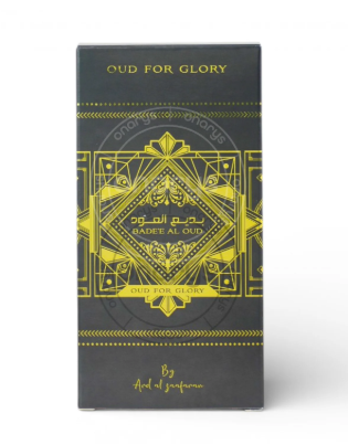 A tall rectangular product box with a dark charcoal gray background and ornate gold geometric artwork and text. Visible text includes 'OUD FOR GLORY' at the top and 'By And of perfume' near the bottom.