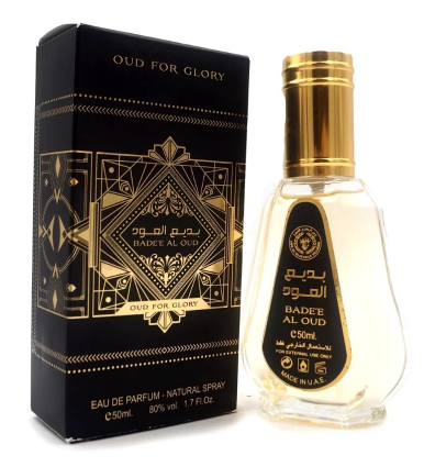 A bottle of Oud For Glory Badee Al Oud Eau De Parfum next to its black and gold packaging box, on a white background.