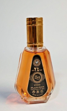 A clear glass bottle of traditional Arabic perfume with amber-colored liquid inside, featuring a metallic gold cap and a black label with gold Arabic calligraphy.
