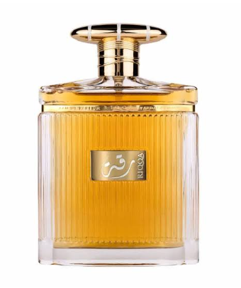 A clear glass perfume bottle with vertical ribbing, filled with golden amber liquid and topped with a gold cap. A gold label on the front features Arabic calligraphy and the brand name 'RICOQA'.