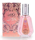 Heibah Eau de Parfum bottle with a rectangular clear glass body, light peach-pink liquid, a metallic rose gold cap, and a matching pink ribbon tag, shown on a white background.