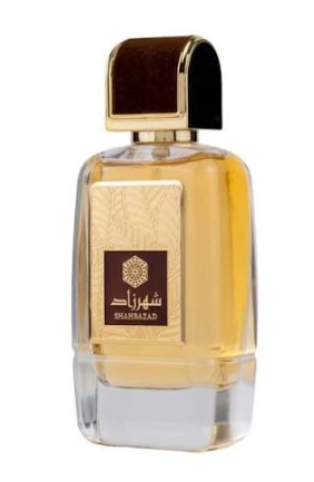 A rectangular glass perfume bottle filled with amber-colored liquid, featuring a gold-toned front label with Arabic script and the brand name SHAHBAZAD, topped with a dark brown and black arched cap, isolated on a white background.