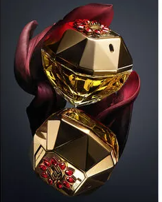 Two faceted perfume bottles with a metallic gold finish and deep red sculpted petals, shown against a dark gradient background.