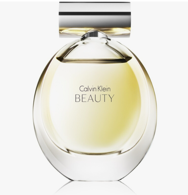 Calvin Klein Beauty Eau de Toilette perfume bottle with a clear, rounded glass body showing pale yellow liquid inside, a silver metallic cap, and the brand name printed in black on the front, set against a light gray background.