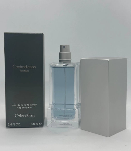 Calvin Klein Contradiction for men Eau de Toilette spray bottle with its dark gray box and a blank gray cube prop, set against a light gray background.