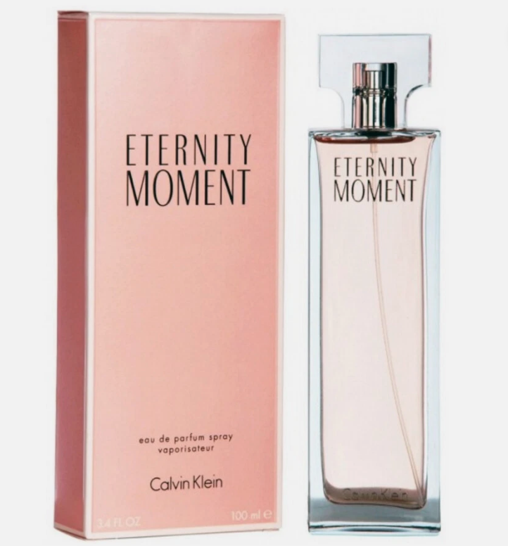 Calvin Klein Eternity Moment Eau de Parfum spray bottle next to its pink packaging box, on a light gray background.