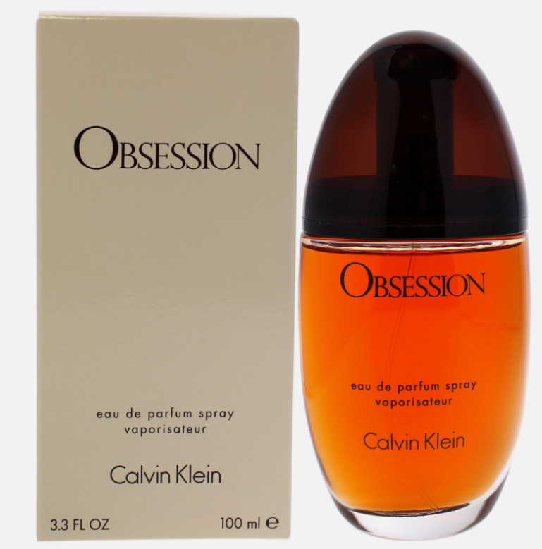 Calvin Klein Obsession Eau de Parfum spray bottle next to its beige packaging box, featuring amber-colored fragrance liquid and a dark amber cap.