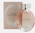 Calvin Klein Sheer Beauty Eau de Toilette spray bottle in front of its matching beige packaging box, featuring a transparent pink-tinted glass bottle with a clear cap and silver collar.