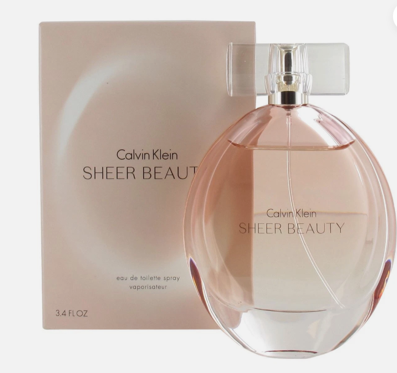 Calvin Klein Sheer Beauty Eau de Toilette spray bottle in front of its matching beige packaging box, featuring a transparent pink-tinted glass bottle with a clear cap and silver collar.