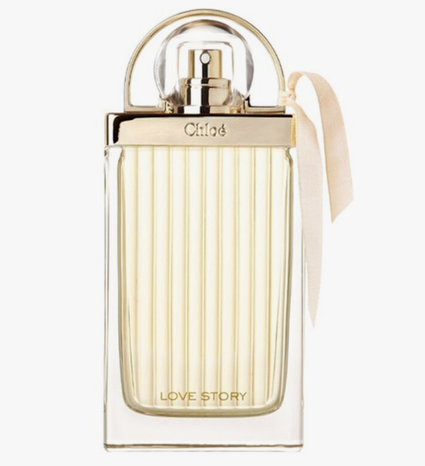Chloé Love Story Eau de Toilette perfume bottle with a clear ribbed glass body, gold-tone cap and collar, and a pale blush ribbon tied on the side, shown on a white background.