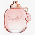 A pink Coach Carriage Eau de Parfum bottle with a metallic rose gold cap and a pink flower charm on a white background.