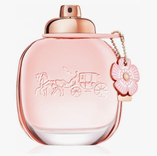 A pink Coach Carriage Eau de Parfum bottle with a metallic rose gold cap and a pink flower charm on a white background.