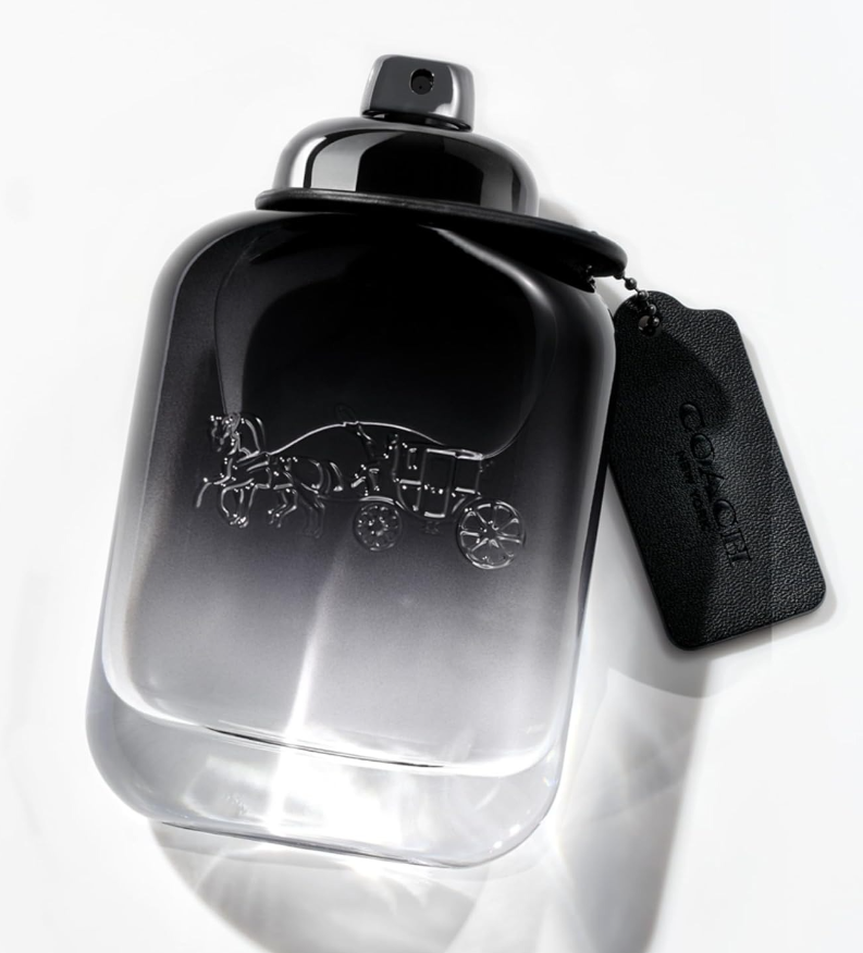 A clear glass perfume bottle with a black spray top and a black hangtag, featuring an embossed horse-drawn carriage motif on the front. The tag reads COACH NEW YORK.