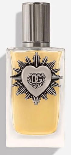 A bottle of Dolce & Gabbana perfume with a silver cap and a silver heart-and-sunburst emblem on the front, filled with pale yellow liquid, shown against a light gray background.