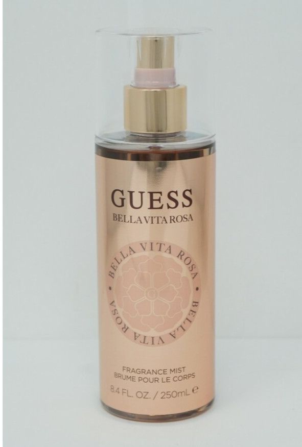 A bottle of GUESS Bellavetta Rosa Fragrance Mist with a metallic rose gold label, gold pump, and clear cap, set against a plain light gray background.