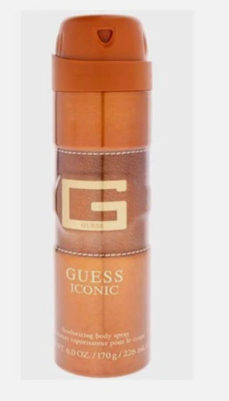 Guess Iconic moisturizing body spray in a metallic copper-brown aerosol can with a gold 'G' logo and white text, shown against a light gray background.