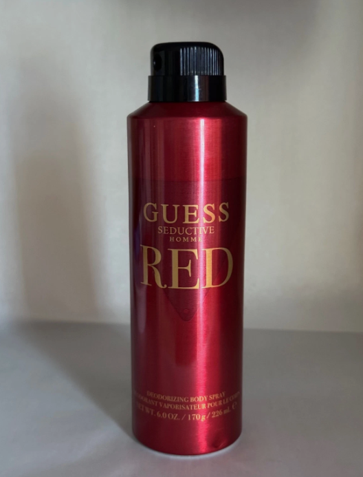 A red aerosol can of Guess Seductive Body Red deodorant spray with gold lettering and a black cap, set against a plain light beige background.