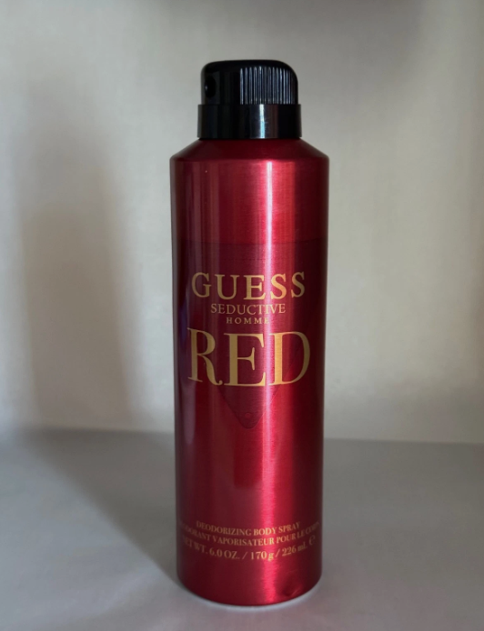 A red aerosol can of Guess Seductive Homme body spray with gold lettering and a black cap, set against a plain light background.