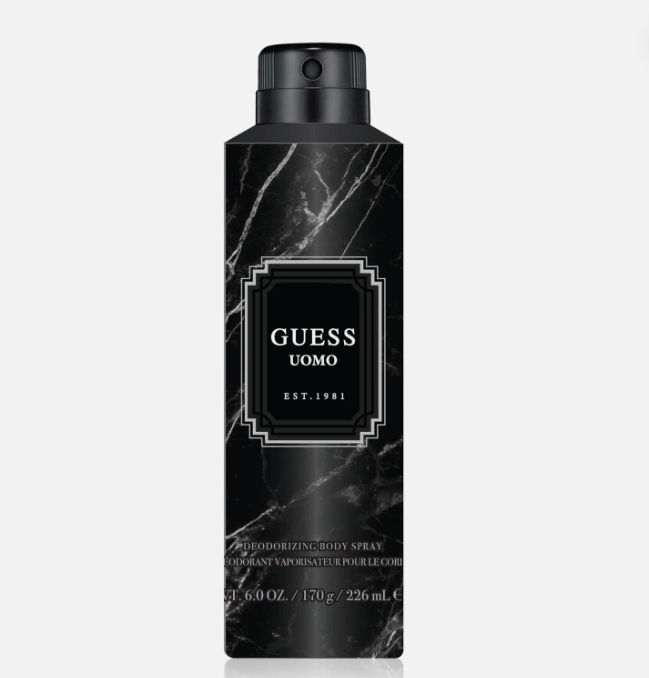 A black Guess Uomo deodorant body spray can with a black marble pattern and a central gold-bordered label, set against a light gray background.
