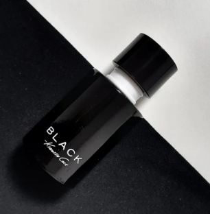 A small black cylindrical bottle with a glossy black cap, labeled 'BLACK Hair Oil' in white text, photographed diagonally on a split black and white background.