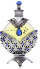 A decorative perfume bottle with a silver-toned ornate base and neck, a pale yellow body, and blue gemstone accents. The bottle has Arabic calligraphy on the front and the text 'KHADLA' visible on the upper body.