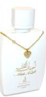 A white perfume bottle with gold Arabic lettering and a gold heart-shaped pendant necklace draped over the neck, set against a plain white background.