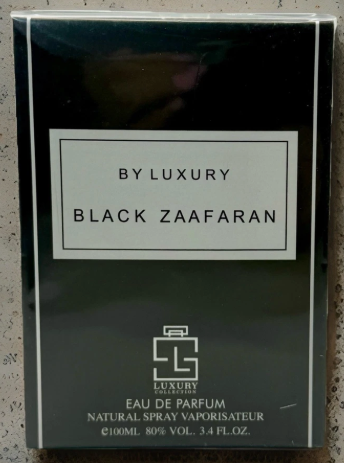 A boxed fragrance product labeled 'BY LUXURY BLACK ZAAFARAN' with a small perfume bottle graphic and text reading 'EAU DE PARFUM' and 'NATURAL SPRAY VAPORISATEUR' on a speckled light surface.