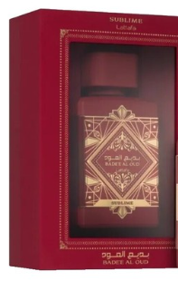A red rectangular gift box with a clear front window displaying a dark red perfume bottle. The bottle has ornate gold geometric detailing and Arabic text, including 'SUBLIME' at the top and 'MADE IN OMAN' at the bottom.