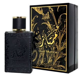 A bottle of Oud Mumtz perfume next to its black and gold presentation box, featuring Arabic calligraphy and gold floral designs.