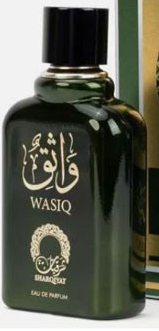 A dark green glass bottle of Wasiq Shams El-Ghazal Eau De Parfum with a black cap, featuring gold Arabic calligraphy and 'WASIQ' branding on the front, shown next to its packaging box.