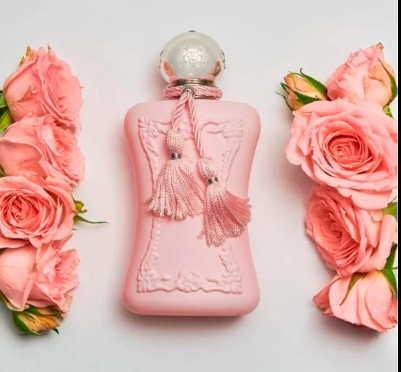 A pink perfume bottle with a sculpted embossed design and two decorative tassels, styled with pink roses on a white background.