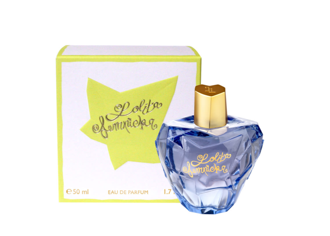 A bottle of Lolita Lempicka Mon Premier Eau de Parfum next to its packaging box. The perfume bottle is faceted blue glass with a gold cap and gold lettering, while the box is white with a lime green star graphic and gold lettering.