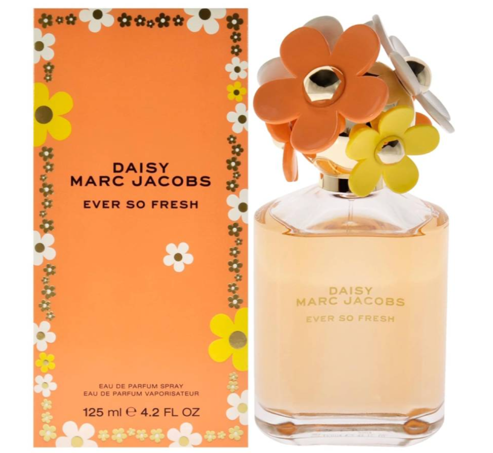 Daisy Marc Jacobs Ever So Fresh Eau de Parfum bottle with its orange packaging box. The bottle features a large, colorful flower cap in shades of orange, yellow, and white, while the box has a matching orange background decorated with white and yellow daisy flowers.