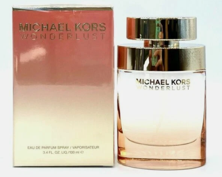 Michael Kors Wonderlust Eau de Parfum spray bottle next to its original packaging box. The bottle features a gradient from pink to clear, with a shiny gold cap, while the box has a pink-to-gold gradient with gold lettering.