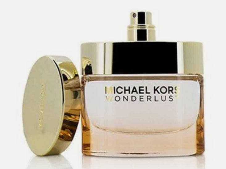 Michael Kors Wonderlus perfume bottle with a gold cap and a separate gold cap leaning against it on a white background.