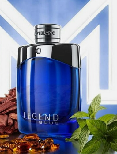 A bottle of Montblanc Legend Blue cologne, featuring a translucent blue glass bottle with a glossy black cap, set against a blue and white geometric background with mint leaves and amber liquid accents.