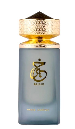 A bottle of Khair Paris Corps fragrance with a frosted light blue-gray glass body, a textured metallic gold cap, and gold lettering on the front.