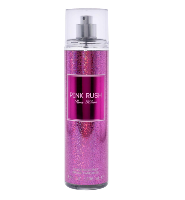 A bottle of Paris Hilton PINK RUSH body spray with a metallic pink glitter finish and a clear cap, shown on a plain white background.