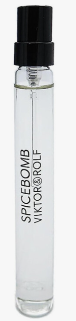 A clear glass perfume spray bottle with a black atomizer cap, containing clear liquid. The bottle is printed with the text 'SPICEBOMB VIKTOR@ROLF' in black vertical lettering, set against a plain white background.
