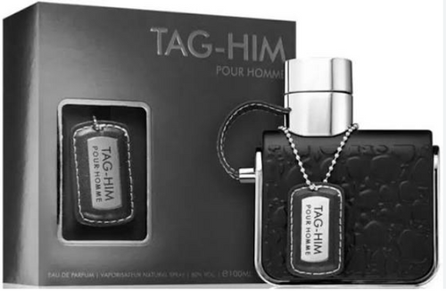TAG-HIM Pour Homme fragrance shown with its black retail box and a black textured perfume bottle featuring a silver cap and a dog-tag style label.